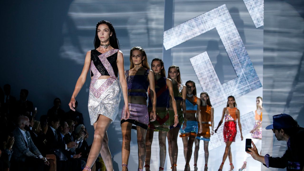 starsza modelka w garniturze defilująca pewnie po długim wybiegu