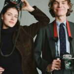 Elegancka kobieta w sukni vintage pozuje przed starym aparatem studyjnym