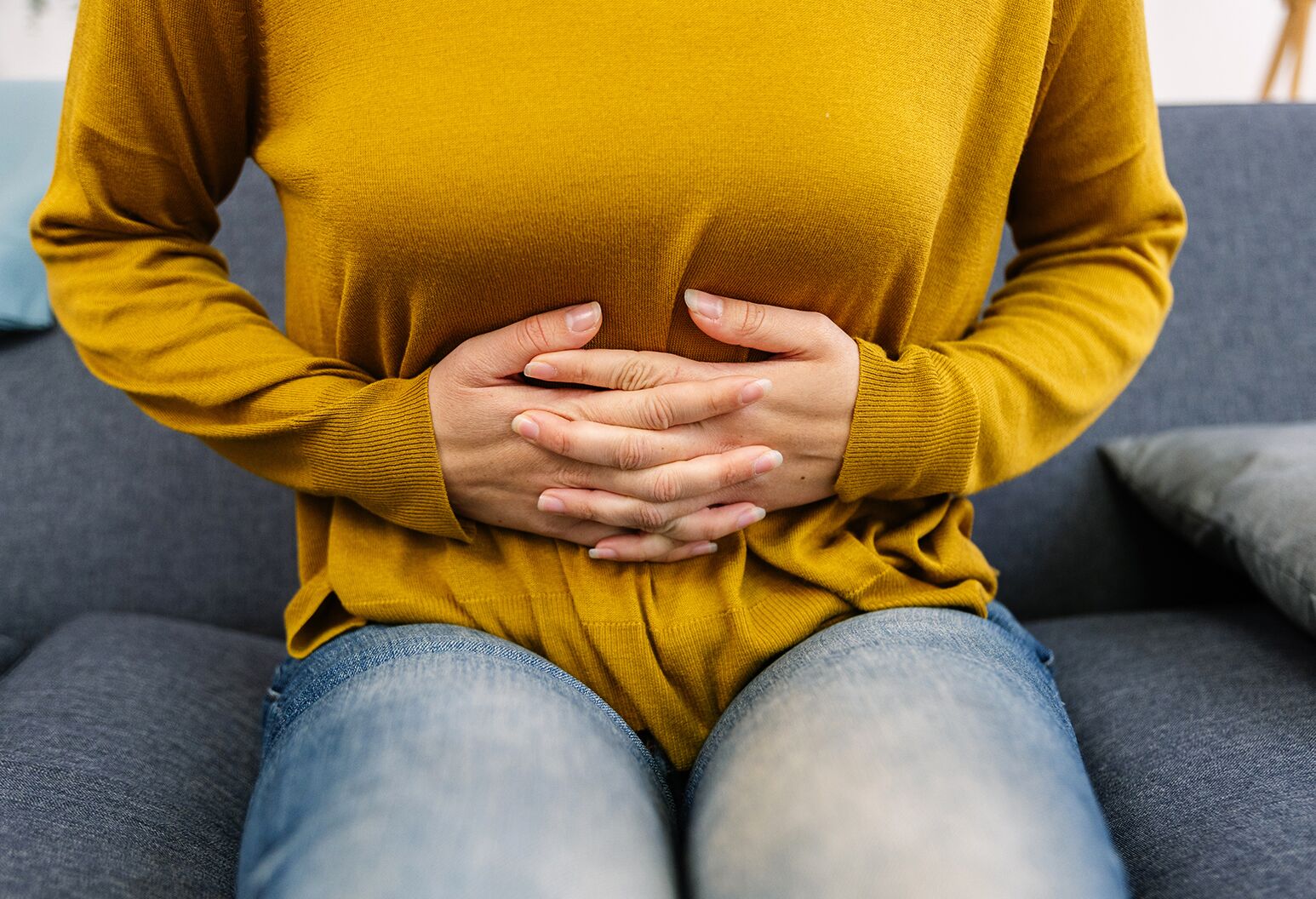 rezygnacja z kawy przeciw stresowi osoba unika kawy wlewając herbatę trzymając brzuch przy stole