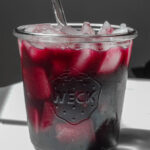 Szklanka z żółtym domowym izotonikiem, plaster cytryny i miód obok na stole