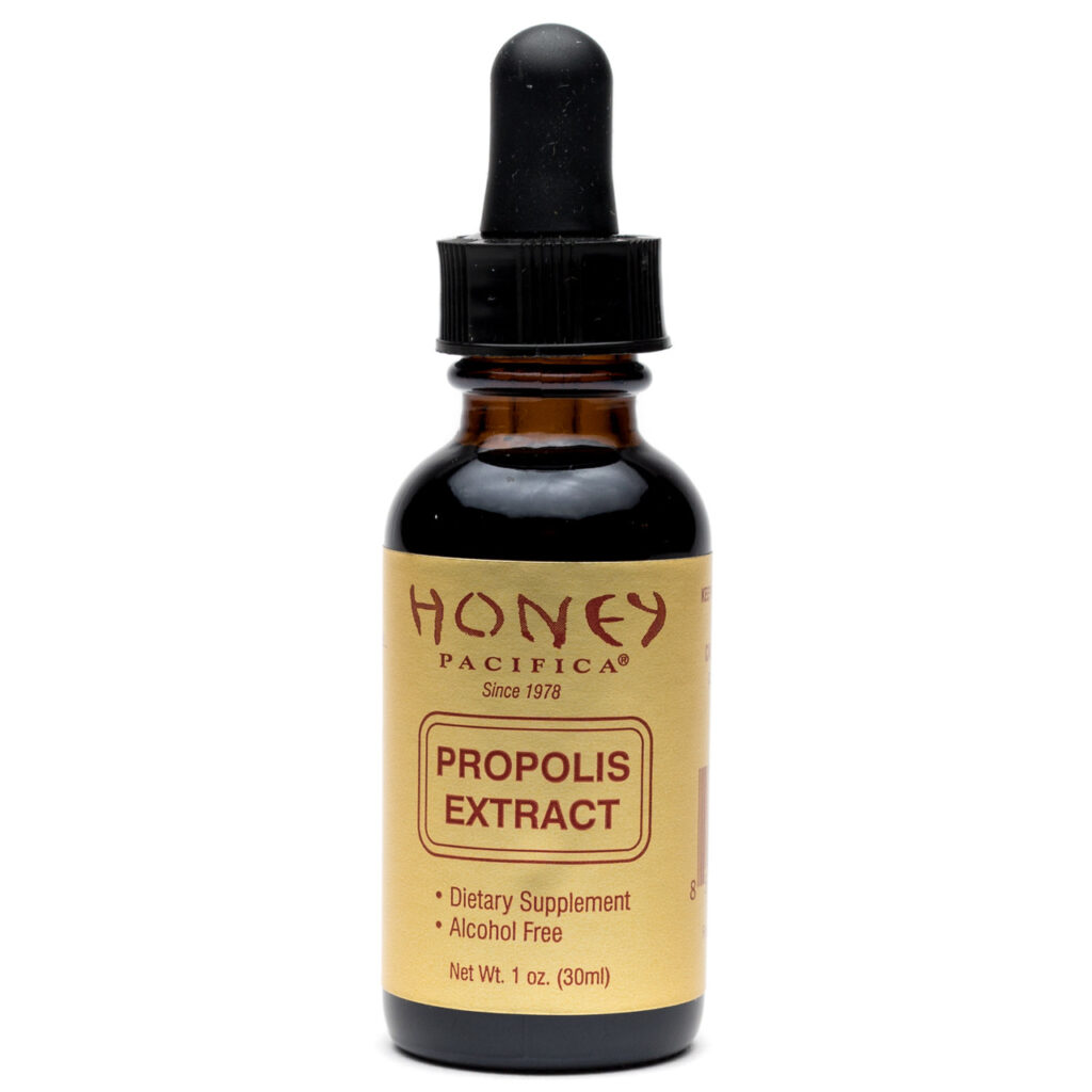 buteleczka propolisu w kroplach z kroplomierzem obok ula pszczelego na stole